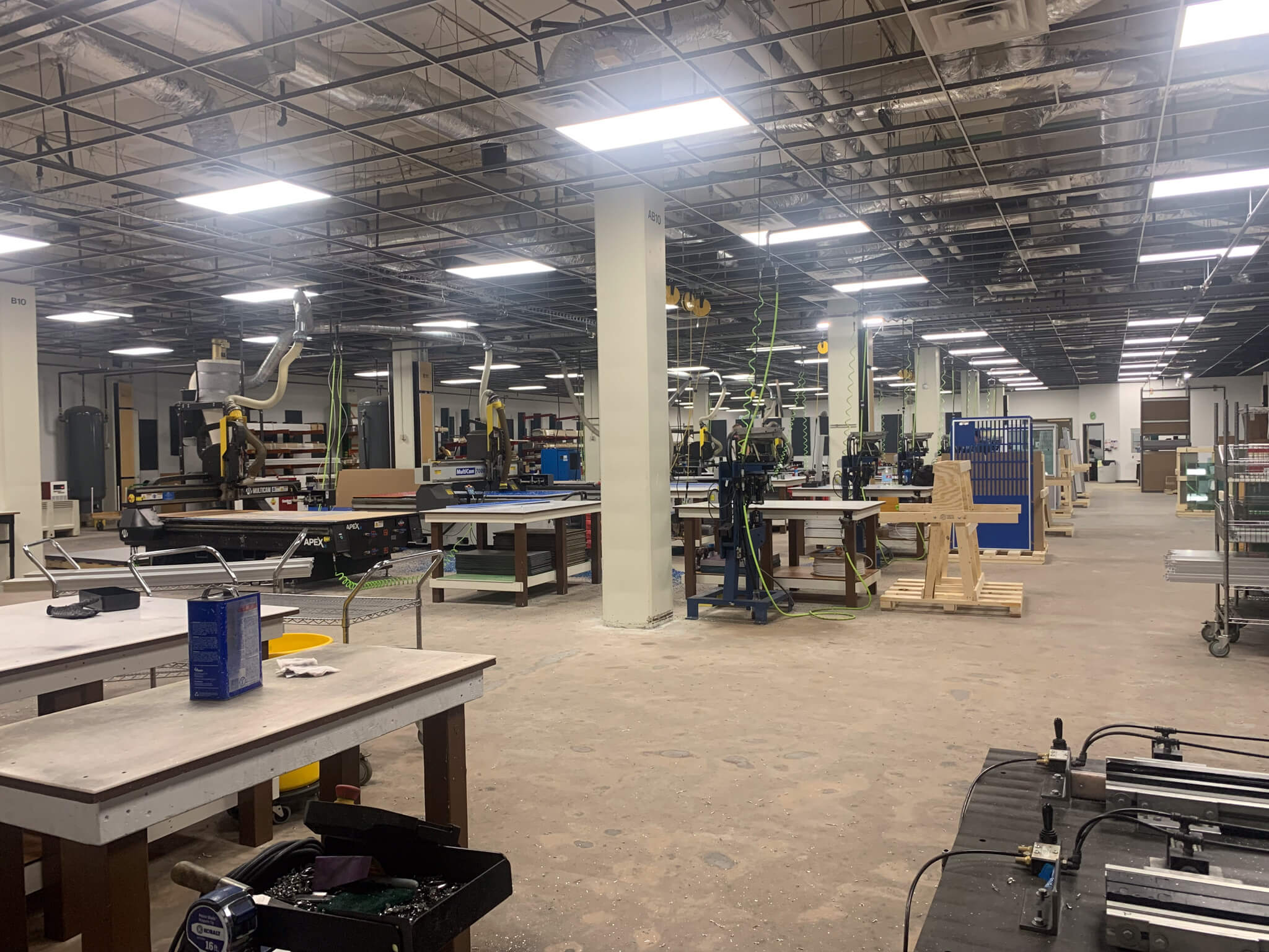 Manufacturing space of Gator Kennels. Multiple machines visible including CNC Routers, Dust Collectors, and assembly benches.